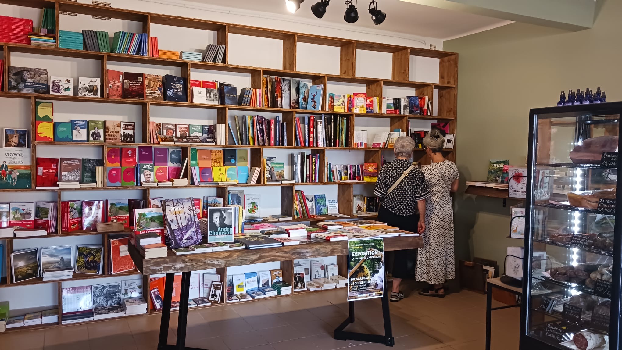Le coin librairie de L'Épicerie qui fait lire : de grandes étagères en bois remplies de livres, dont un rayon sur les Cévennes et le chemin de Stevenson