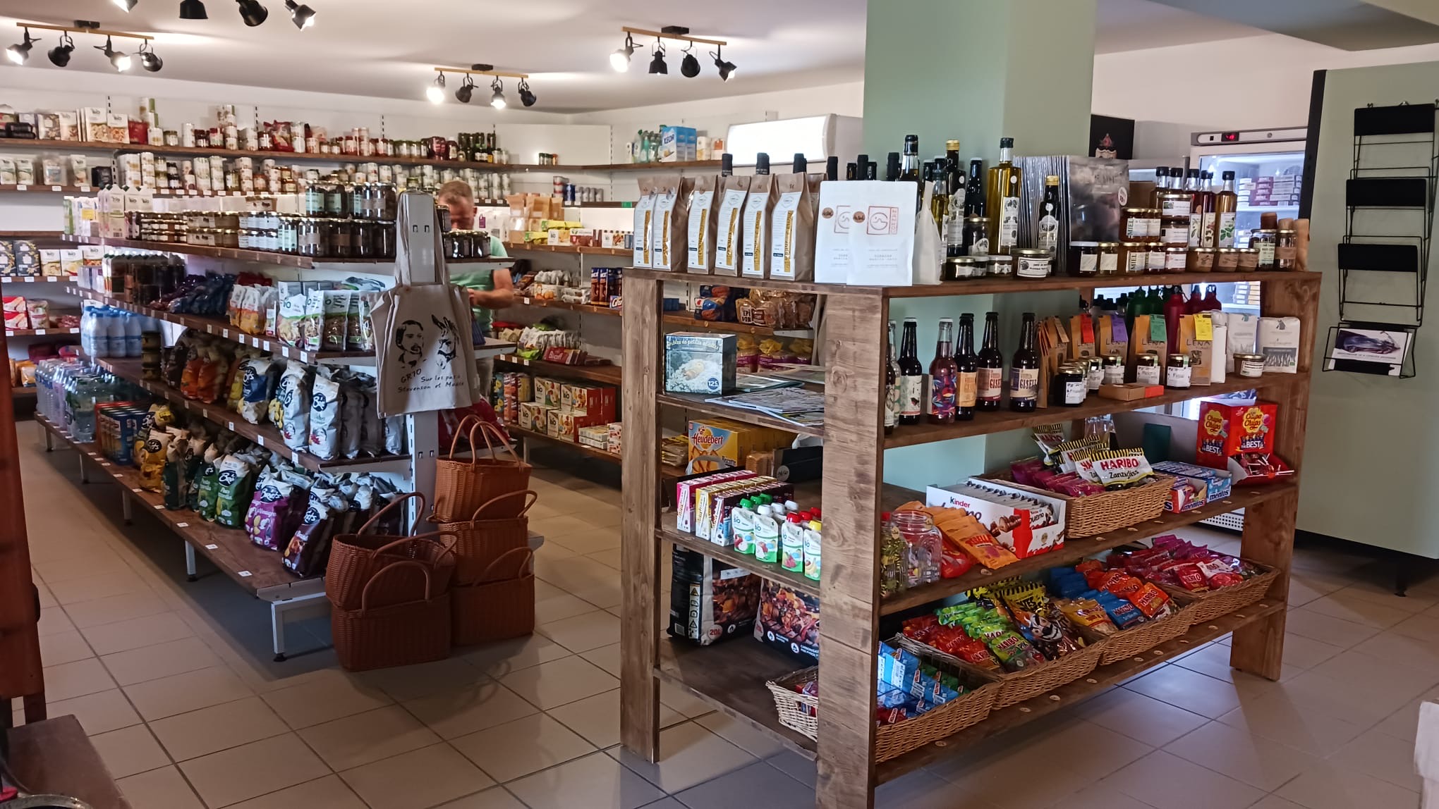L'intérieur de L'Épicerie qui fait lire : les rayons en bois garnis de produits locaux, cafés en grains, bières et épicerie fine